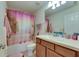 Well-lit bathroom with wood cabinets, sink, toilet, and shower with pink curtain at 5312 Sylvester Loop, Tampa, FL 33610