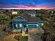 Aerial view of a two-story home with a three-car garage, inviting front porch, and lush landscaping at 613 Manns Harbor Dr, Apollo Beach, FL 33572