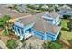 Eye-catching blue exterior features a three-car garage, covered porch, and mature landscaping at 613 Manns Harbor Dr, Apollo Beach, FL 33572