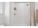 Bright bathroom showcasing a tiled shower with glass shelves and neutral shower curtain at 6930 Ripple Pond Loop, Zephyrhills, FL 33541