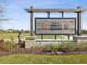 Entrance to Villas at Abbott Square features a rustic wood sign, decorative stone pillars, and lush green space at 6930 Ripple Pond Loop, Zephyrhills, FL 33541