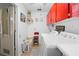 Well-lit laundry room with red cabinets, a utility sink, modern appliances, and a folding station at 8518 Delaware Dr, Weeki Wachee, FL 34607