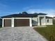 Completed new construction home with a three-car garage, paver driveway, and modern exterior design at 9 Tee View Rd, Rotonda West, FL 33947