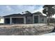 New construction home with a three-car garage, dark roof, and modern architectural details set against a sunny sky at 9 Tee View Rd, Rotonda West, FL 33947