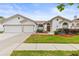 Charming single-story home featuring a well-manicured lawn and a two-car garage under a clear blue sky at 9408 Bluebird Dr, Tampa, FL 33647