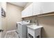 Functional laundry room featuring a sink, washer, dryer, and storage cabinets above at 9408 Bluebird Dr, Tampa, FL 33647