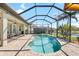 Screened pool and spa with brick paved deck and outdoor kitchen overlooks the landscaped backyard and golf course at 1038 Grouse Way, Venice, FL 34285