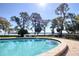 Sparkling pool with a lake view, surrounded by trees, landscaping and comfortable lounge chairs at 1111 N Bayshore Blvd # F11, Clearwater, FL 33759