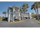 Condo building with grey accents, palm trees, and a parking area in sunny weather at 12055 3Rd E St # 103, Treasure Island, FL 33706