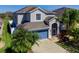 View of the attractive two-story home with a blue garage door and mature palm trees in the landscaping at 12310 Juniper Field Ct, Riverview, FL 33579