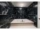 Luxurious bathroom featuring a deep soaking tub surrounded by stunning black marble tiling at 1560 Gulf Blvd # 1104, Clearwater Beach, FL 33767
