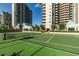 Well-maintained tennis court with high-rise buildings in the background, surrounded by lush green trees at 1560 Gulf Blvd # 1104, Clearwater Beach, FL 33767
