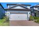 Exterior view of a home featuring a two-car garage and brick paver driveway with landscaped yard at 17805 Everlong Dr, Land O Lakes, FL 34638