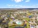 Aerial view of neighborhood featuring housing with mature trees, a pond, community pool, and tennis courts on a sunny day at 24510 Mason Ct, Lutz, FL 33559