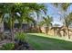 Expansive backyard featuring lush green grass, beautiful tropical landscaping, and a wooden fence at 3416 Fairfield Trl, Clearwater, FL 33761