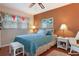 Cozy bedroom with blue bedding and hardwood floors, illuminated by bedside lamps and a window at 3416 Fairfield Trl, Clearwater, FL 33761