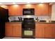 Well-lit kitchen featuring wooden cabinets, black appliances, and neutral countertops at 3416 Fairfield Trl, Clearwater, FL 33761