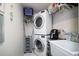 A modern laundry room featuring a stacked washer and dryer with a utility sink and added storage space at 3416 Fairfield Trl, Clearwater, FL 33761
