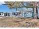Quaint single-story home with a charming pink door and a cozy front porch beneath a mature tree at 4111 Moog Rd, Holiday, FL 34691