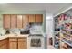 Functional kitchen features wooden cabinetry, white appliances, tile backsplash and walk-in pantry space at 4111 Moog Rd, Holiday, FL 34691