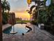 Backyard view with a private pool, lush landscaping, and stunning sunset over the waterfront at 5241 West Shore Dr, New Port Richey, FL 34652