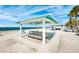 Beachfront picnic area featuring covered picnic tables with views of the ocean, white sandy beach, and blue skies at 5241 West Shore Dr, New Port Richey, FL 34652