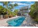 Gorgeous outdoor pool with tropical landscaping, with views of the balconies of the multi-story home at 5241 West Shore Dr, New Port Richey, FL 34652