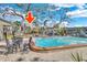 Community swimming pool with patio and lounge chairs, next to shade trees and condo buildings at 702 Lyndhurst St # 823, Dunedin, FL 34698