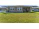 Backyard view of the screened lanai of the home with large grassy area at 7096 Heron Walk Ln, Wesley Chapel, FL 33545