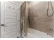 Bathroom featuring tub with tiled walls and white door with silver hardware at 7096 Heron Walk Ln, Wesley Chapel, FL 33545
