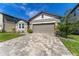 Eye-level of attractive single-story home with paved driveway, and stone detailing on facade at 7096 Heron Walk Ln, Wesley Chapel, FL 33545