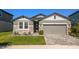 Charming single-story home featuring a well-manicured lawn, stone accents, and a two-car garage at 7096 Heron Walk Ln, Wesley Chapel, FL 33545