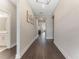 Long hallway with wood floors, neutral paint, modern light fixture, and artwork at 7096 Heron Walk Ln, Wesley Chapel, FL 33545