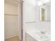 Bright bathroom featuring a white vanity, sink, mirror and walk-in closet with wooden shelving at 8001 Jasmine Dr # 8001, Temple Terrace, FL 33637