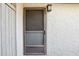 Close-up of a screen door with a dark frame, set against a textured, light-colored exterior wall and a wall mount light at 8001 Jasmine Dr # 8001, Temple Terrace, FL 33637