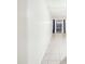 Hallway features neutral tile floors, white walls and a glass sliding door with dark blue curtains at the end of the hall at 8001 Jasmine Dr # 8001, Temple Terrace, FL 33637
