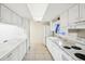 Compact kitchen with white cabinets, appliances, and tile flooring, illuminated by a bright ceiling light at 8001 Jasmine Dr # 8001, Temple Terrace, FL 33637