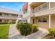 Exterior view of a condo building with white staircase, tan siding, and green shrubs at 10038 62Nd N Ter # 1, St Petersburg, FL 33708
