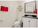 Chic half-bathroom with dark granite countertop, white cabinets, decorative mirror and wall accents at 12225 Lake Blvd, New Port Richey, FL 34655