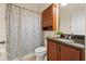 Bathroom featuring a granite countertop vanity, wood cabinets, and a shower with a patterned curtain at 12225 Lake Blvd, New Port Richey, FL 34655