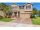 Charming two-story home showcasing a manicured lawn, stone accents, and a brick driveway at 12225 Lake Blvd, New Port Richey, FL 34655