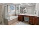 A luxurious bathroom featuring double sinks, vanity, tub, shower, and neutral tiling with updated fixtures at 14841 Tudor Chase Dr, Tampa, FL 33626