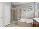 A well-lit bathroom with a glass-enclosed shower, soaking tub, and tiled walls at 14841 Tudor Chase Dr, Tampa, FL 33626