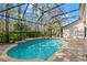 The screened pool offers a refreshing outdoor oasis with brick pavers and views of the surrounding lush landscape at 14841 Tudor Chase Dr, Tampa, FL 33626