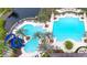 Aerial view of a community pool featuring a water slide, palm trees, lounge chairs, and a pristine blue swimming pool at 14841 Tudor Chase Dr, Tampa, FL 33626