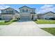 Two-story home featuring a neutral color palette, well-manicured lawn and concrete driveway leading to a garage at 35542 Buttonweed, Zephyrhills, FL 33541