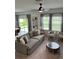 Bright and airy living room featuring comfortable seating, a modern ceiling fan, and large windows at 35542 Buttonweed, Zephyrhills, FL 33541