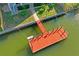 Aerial view of a red wooden dock on the canal surrounded by green water and the property's manicured yard at 5100 Cedarbrook, Hernando Beach, FL 34607