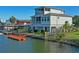 Exterior of the two-story waterfront home featuring a dock, manicured lawn, and fenced yard at 5100 Cedarbrook, Hernando Beach, FL 34607