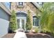 Stone-clad facade with arched entry and white double doors accented with decorative trees at 5115 Abisher Wood Ln, Brandon, FL 33511